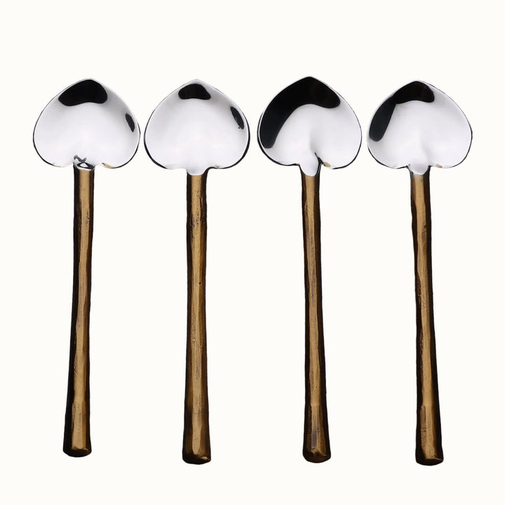 Four heart spoons with metal handles and metal ends on a wooden surface