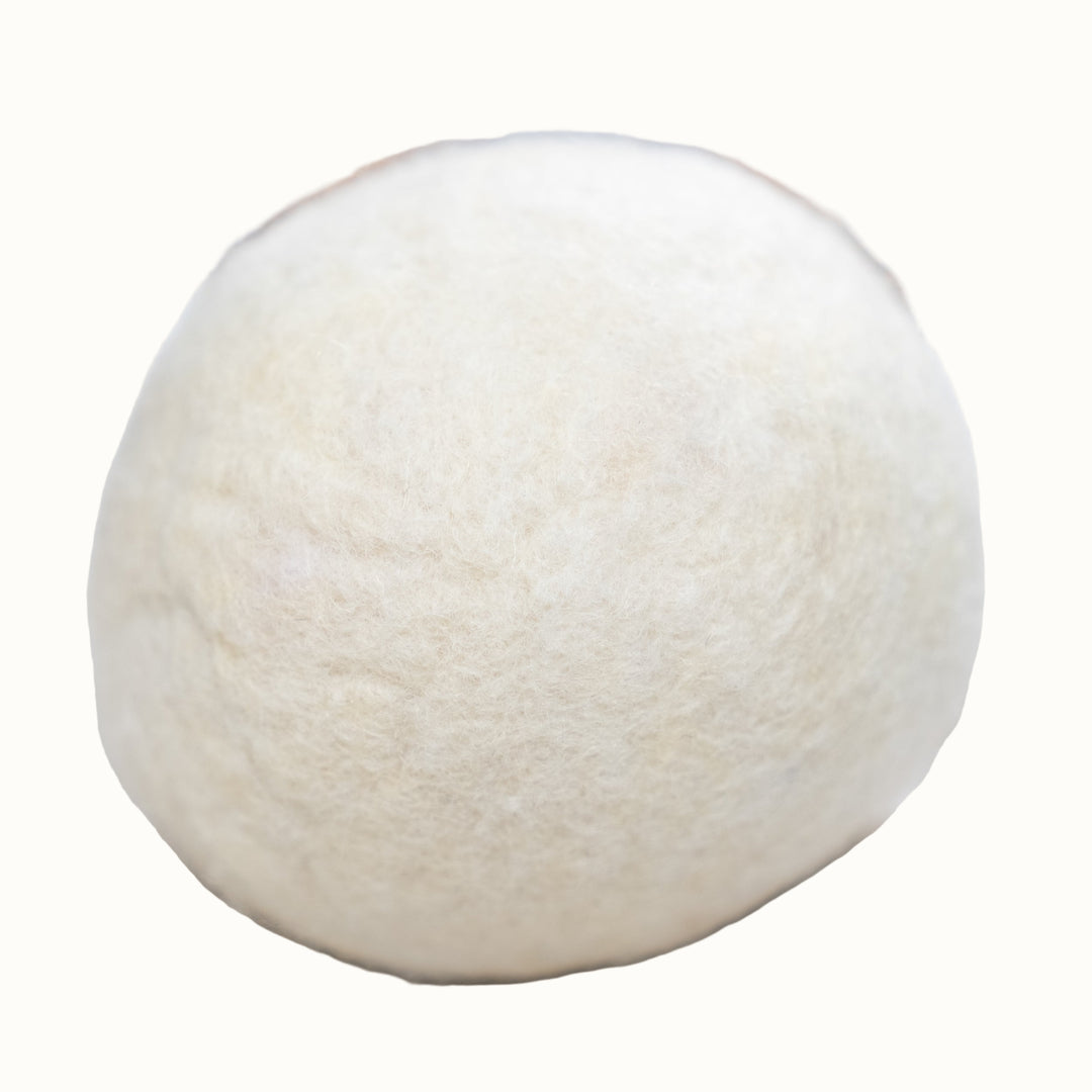 White wool dryer ball on a wooden surface with a blurred background