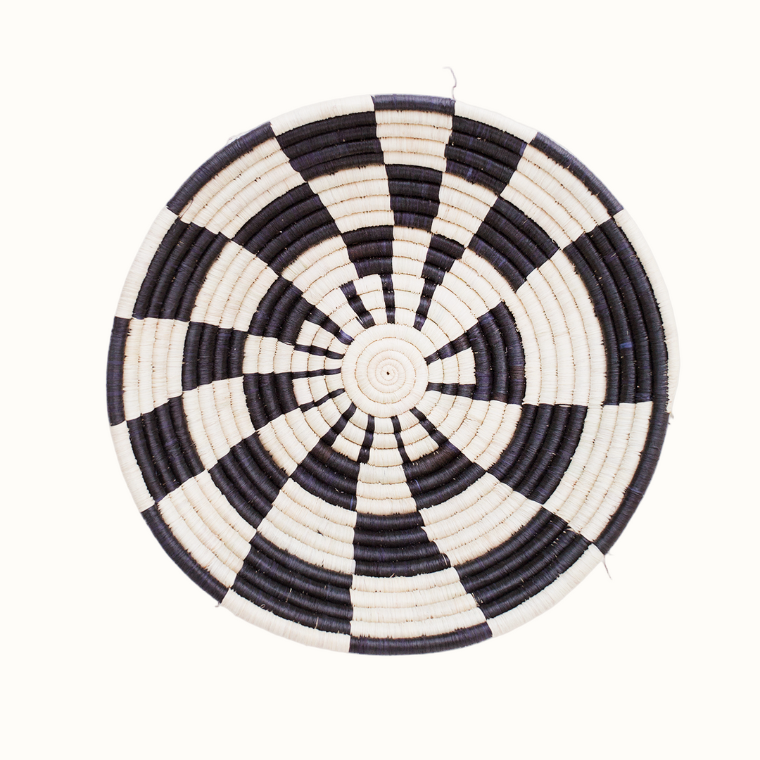 Black and white woven circular basket on a white background